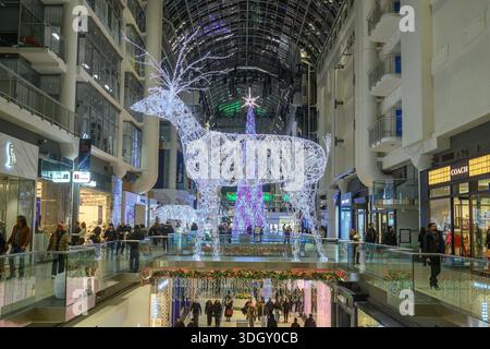 Toronto, ON, Kanada - 24. Dezember 2025: Große beleuchtete Rentiere und Weihnachtsbäume schmücken ein mehrstöckiges Einkaufszentrum Stockfoto