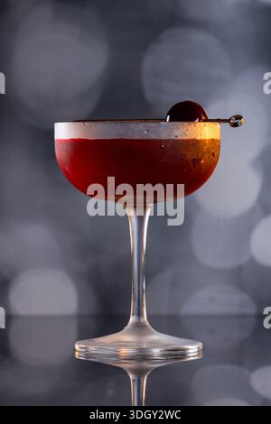 Manhattan Cocktail serviert mit einer Bordeauxkirsche und einem Orangengeschmack Stockfoto
