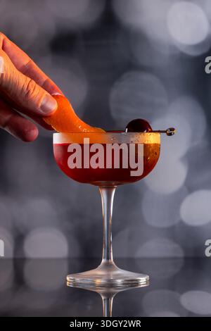 Manhattan Cocktail serviert mit einer Bordeauxkirsche und einem Orangengeschmack Stockfoto