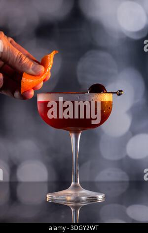 Manhattan Cocktail serviert mit einer Bordeauxkirsche und einem Orangengeschmack Stockfoto