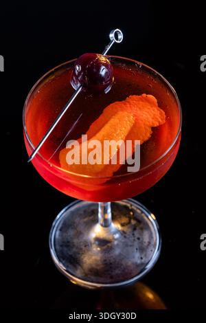 Manhattan Cocktail serviert mit einer Bordeauxkirsche und einem Orangengeschmack Stockfoto