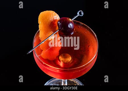 Manhattan Cocktail serviert mit einer Bordeauxkirsche und einem Orangengeschmack Stockfoto