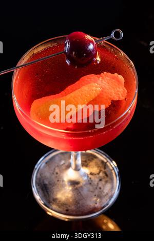 Manhattan Cocktail serviert mit einer Bordeauxkirsche und einem Orangengeschmack Stockfoto