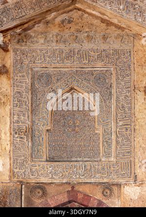 Komplizierte arabische Kalligraphie und Blumensteinschnitzerei an einer alten islamischen Monumentalmauer, Delhi, Indien, 29. Januar 2024 Stockfoto