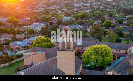 Melbourne, VIC, Australien. Januar 2026. - Ein Luftschuss fängt ein vorstädtisches Wohngebiet während der goldenen Stunde ein gemauerter Turm an Stockfoto
