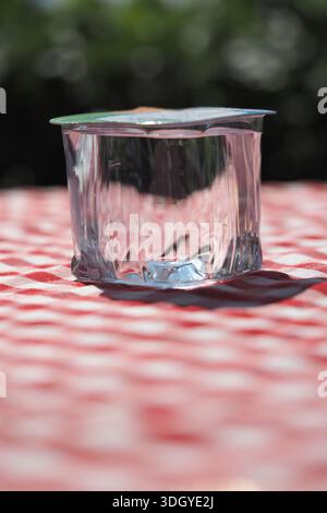 Ein Glas Wasser liegt draußen auf einer karierten Tischdecke Stockfoto