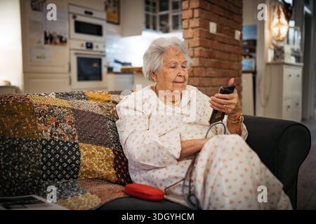 Ältere Frau, die allein zuhause fernsieht. Stockfoto