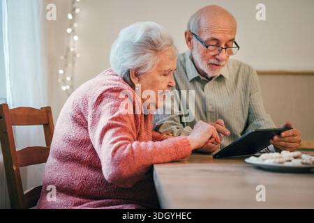 Senior-Mann und -Frau, die online mit Tablet reservieren. Stockfoto