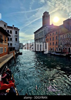 Golden-Hour-Blick auf eine Gondel, die durch einen Kanal mit historischen Gebäuden fährt, Venedig, Italien Stockfoto
