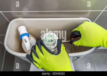 Nahaufnahme auf einem Klempner, der eine Toilette im Badezimmer repariert.Home Repair Concepts Stockfoto