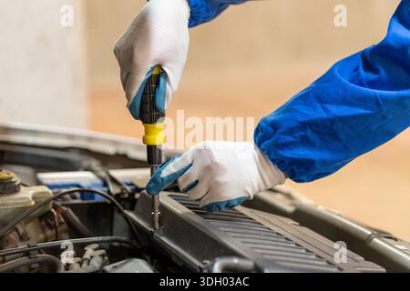 Kfz-Mechaniker-Hände und Schraubendreher-Werkzeuge arbeiten an der Kfz-Leistung. Junger Mann Motortechniker, Reparatur Service und Wartung Fahrzeug Maschine Stockfoto