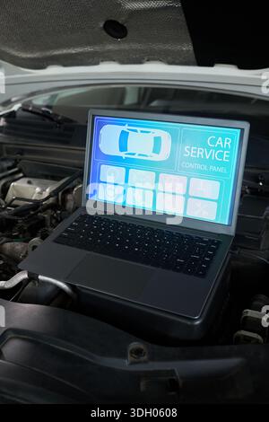 Laptop mit digitalem Bedienpult im Motorraum, mit Diagnoseschnittstelle mit Fahrzeugdiagramm und Wartungssymbolen für Autoreparaturen Stockfoto