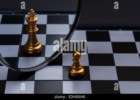 Schachfigur, der sein Spiegelbild auf einem Spiegel sieht und sich selbst als König sieht, denke groß. Stockfoto