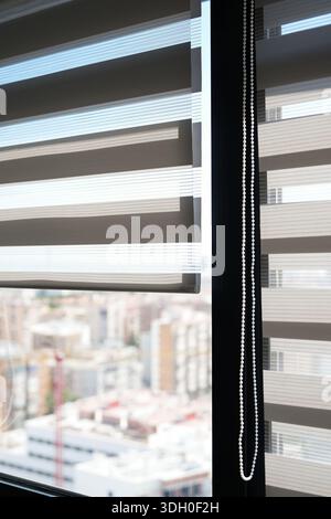 Moderne Jalousien mit weichem Tageslicht und verschwommenem Blick auf die Stadt schaffen einen sauberen Innenraum-Bürohintergrund Stockfoto
