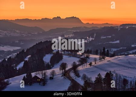 Malerische alpine Landschaft bei Sonnenuntergang im Bregenzerwald mit dem Säntis im Hintergrund, warmes goldenes Licht, dramatischer Himmel und friedlicher mou Stockfoto