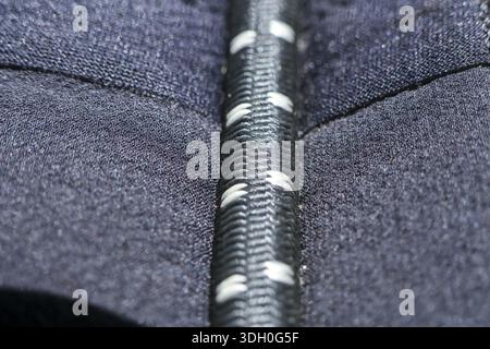 Detaillierte Makroansicht der schwarzen elastischen Kordel mit weißem Strichmuster auf dunkelblauem texturiertem Material, das ein robustes und sicheres Tragegefühl von Sportbekleidung zeigt Stockfoto