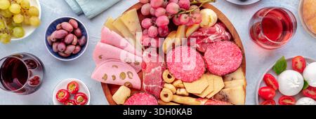 Italienisches Antipasti-Panorama. Wurstplatte mit Käse und anderen Snacks, mit Wein, Oliven, Obst usw. Panoramaaufnahme über Kopf mit Flachlage Stockfoto