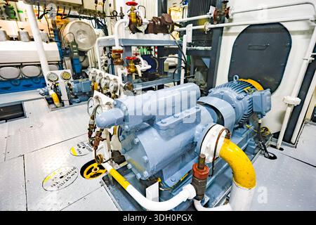 Schiffspumpe mit Elektromotor, Manometern, Ventilen und Rohrleitungen im Maschinenraum des Schiffes, Industriemaschinen und Schiffssysteme. Stockfoto