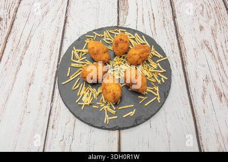 Ein Tablett mit frisch zubereiteten, hausgemachten Kroketten mit unregelmäßigen Formen und einem sprudelnden, goldenen Teig, der außen noch warm und knusprig ist. Stockfoto