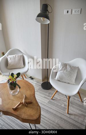 Moderner Wohnbereich mit Stehlampe, eames-Stühlen und einem Kaffeetisch aus Naturholz Stockfoto