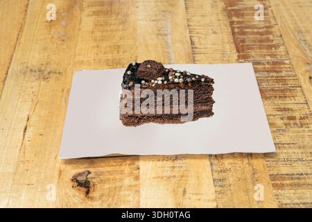 Ein Stillleben mit einem schlichten, glatten 70% Kakaoschokoladenkuchen, begleitet von frischen Himbeeren und einem Minzzweig, Stockfoto