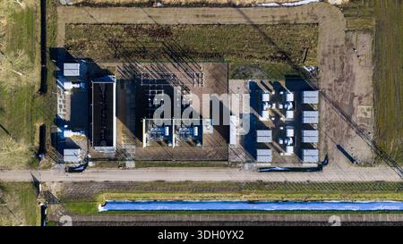 Aus der Vogelperspektive eines elektrischen Umspannwerks, einer Betoninsel inmitten brauner Felder, mit Gebäuden, die starke Schatten werfen, Niederlande. Stockfoto