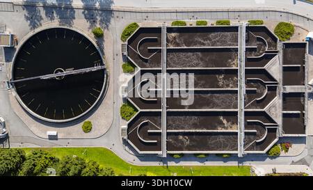 Luftaufnahme einer modernen Abwasseraufbereitungsanlage mit kreisförmigen Tanks und Filtersystemen, die in eine Landschaftsumgebung integriert sind. Stockfoto