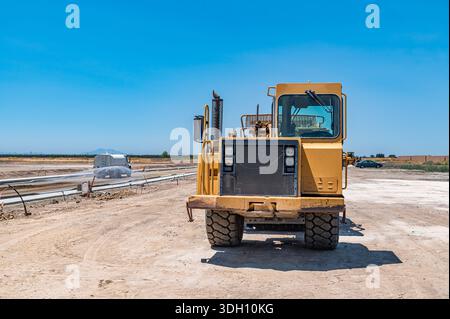 Vorderansicht des großen gelben Traktors. Die Bewässerungsmaschine bewässert die Straße. Autobahnbau. Stockfoto