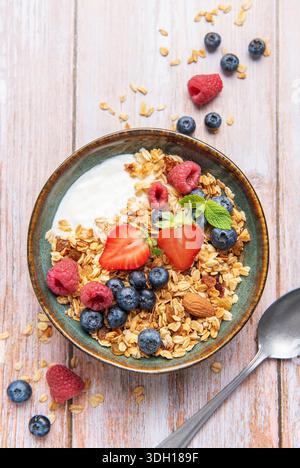 Müsli mit Joghurt, Erdbeeren, Heidelbeeren und Himbeeren in einer Keramikschale Stockfoto