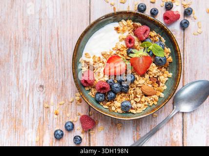 Müsli mit Joghurt, Erdbeeren, Heidelbeeren und Himbeeren in einer Keramikschale Stockfoto