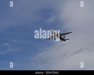Das Flugzeug fliegt gegen den blauen bewölkten Himmel Stockfoto