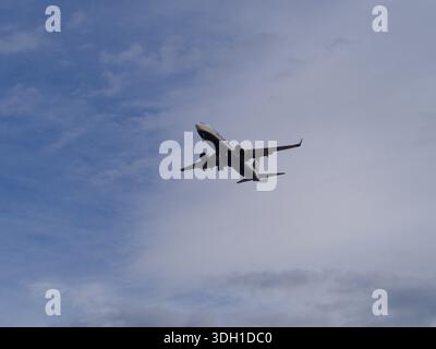 Das Flugzeug fliegt vor blauem bewölktem Himmel Stockfoto