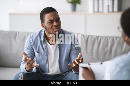 Psychologe hilft depressiven jungen schwarzen Mann, Beratung zu männlichen Patienten im Büro Stockfoto