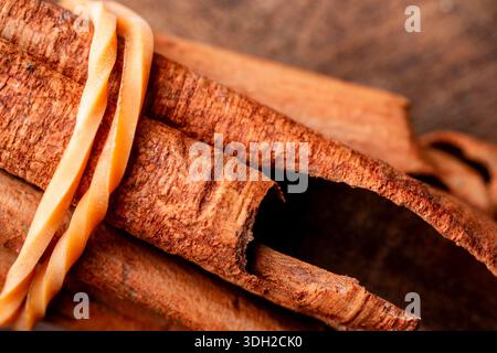 Details von aromatischen Zimtstäbchen mit natürlicher Rindenstruktur, die zum Kochen, Backen oder Kräutermedizin auf einer Holzoberfläche platziert werden. Stockfoto