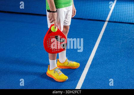 Padel-Spielhalle mit Spieler, der Schläger und Ball in der Nähe des Netzes hält, für Trainingswettbewerbe und Kopierraum Stockfoto