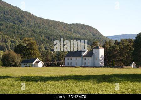Moderne Nostalgie Stille mit weißer Holzkirche auf offener Wiese und bewaldeten Hügeln, klare nordische ländliche Landschaft, die für ihn kulturelle Erinnerungen weckt Stockfoto