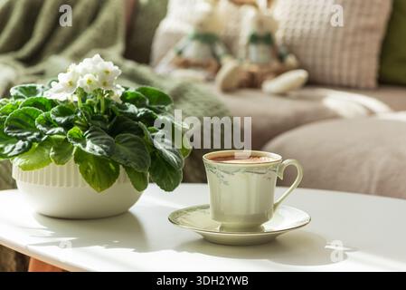 Gemütliches Osterzimmer mit Plüschhasen, Kaffee und Blumen im Sonnenlicht Stockfoto