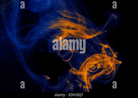 Orangefarbener und blauer Rauch vor schwarzem Hintergrund. Stockfoto