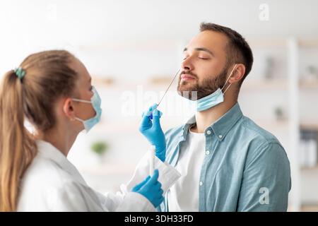 Ärztin, die in der Klinik einen nasalen Coronavirus-PCR-Test für einen Tausendjährigen Mann macht. Konzept zum Schutz von Infektionskrankheiten Stockfoto