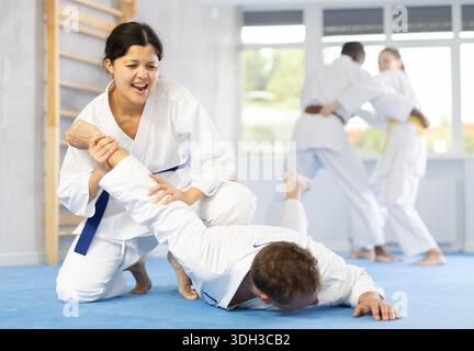 Kosmopolitische Sportler trainieren während des Trainings im Aikido, wie sie Schutz mit wringenden Händen leisten Stockfoto
