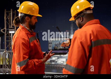 Bohrschiff-Crew analysiert die Leistung der Ausrüstung auf dem Armaturenbrett-Bildschirm des Laptops. Mitarbeiter von Offshore-Plattformen sammeln Brainstorming, überwachen Ölförderraten und Systemdruck mit einem Notebook Stockfoto