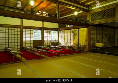 Kyoto, Japan - 17. Oktober 2023: Innenansicht eines Tatami-Zimmers in Tenryu-JI Kohojo mit niedrigen Tischen auf roten Teppichen, Shoji-Bildschirmen und Schiebetüren mit traditionellen japanischen Tiermalereien. Stockfoto