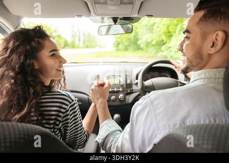 Liebevolles Paar, das die Hände hält, während es im Auto sitzt, Rückansicht Stockfoto