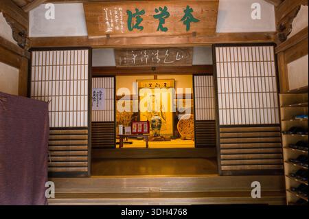 Koya San, Japan - 21. Oktober 2023: Das Bild zeigt das Innere eines traditionellen japanischen Zimmers im Hongaku-in Tempel mit Schiebetüren, Holzarchitektur, einem großen gerahmten Porträt, Kalligraphie und dekorativen Objekten im Inneren. Stockfoto
