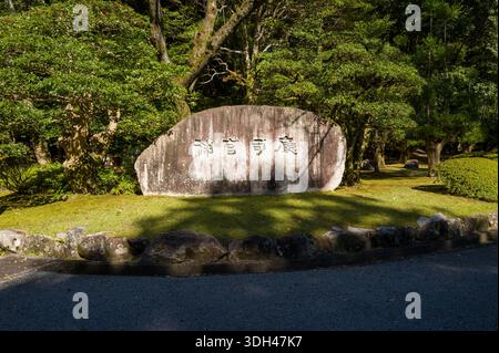 ISE, Japan - 29. Oktober 2023: Große Stele mit japanischer Schrift wird zwischen Bäumen und Grün in einem Landschaftsgarten ausgestellt. Stockfoto