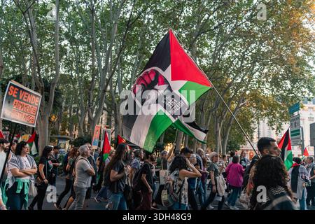 Madrid, Spanien - 15. Oktober 2025: Menschenmassen marschieren mit großen „Freies Palästina“-Fahnen entlang der von Bäumen gesäumten Paseo del Prado. Stockfoto