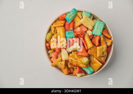 Eine Schüssel mit bunten Snacks in verschiedenen Formen und Größen. Die Schüssel ist mit einer Mischung aus Obst, Gemüse und anderen Snacks gefüllt. Japanischer Reis cra Stockfoto