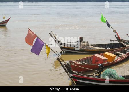 Hölzerne birmanische Fischerboote mit bunten Fahnen auf einem Fluss Stockfoto