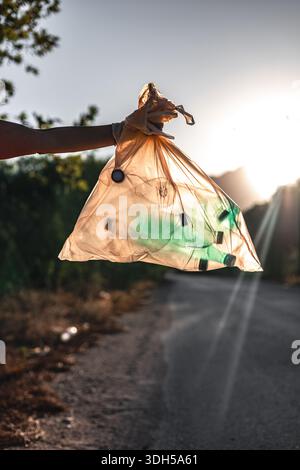 Ein engagierter Freiwilliger sammelt Müll entlang einer malerischen Bergstraße und veranschaulicht die Bemühungen der Gemeinschaft, die natürliche Schönheit zu erhalten und die Umwelt zu fördern Stockfoto