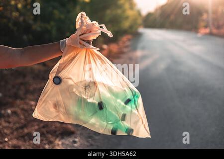 Ein engagierter Freiwilliger sammelt Müll entlang einer malerischen Bergstraße und veranschaulicht die Bemühungen der Gemeinschaft, die natürliche Schönheit zu erhalten und die Umwelt zu fördern Stockfoto
